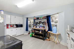 Kitchen with stainless steel appliances, white cabinetry, healthy amount of natural light, and light wood-style floors