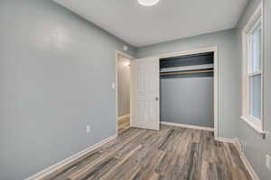 Unfurnished bedroom with wood finished floors and a closet