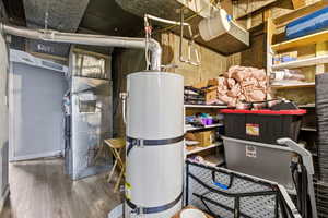 Utility room featuring strapped water heater and heating unit