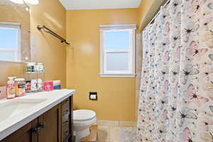 Full bath with vanity, a shower with shower curtain, and light tile patterned flooring