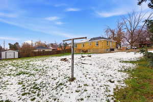 Yard layered in snow with a fenced backyard and a shed