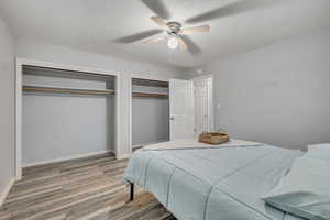 Bedroom with light wood-style floors, two closets, and a ceiling fan