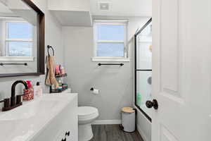 Full bath featuring vanity, dark wood finished floors, and shower / bath combination with glass door