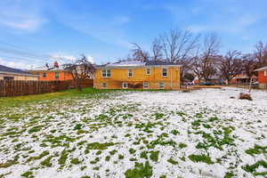 Snow covered property featuring a fenced backyard and brick siding