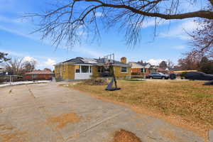 Bungalow with a front yard, roof mounted solar panels, concrete driveway, a chimney, and brick siding