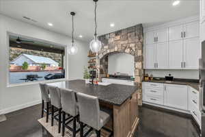 Kitchen featuring white cabinetry, pendant lighting, a kitchen island with sink, dark stone counters, and recessed lighting