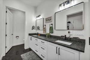 Full bath featuring double vanity and finished concrete floors