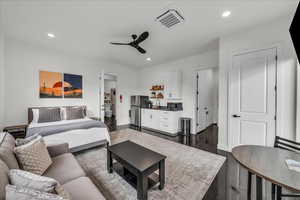 Bedroom featuring cooling unit, freestanding refrigerator, recessed lighting, dark wood-type flooring, and ceiling fan