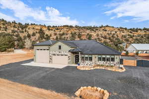 Modern inspired farmhouse featuring stone siding, driveway, a metal roof, a gate, and a garage