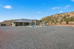 Back of property featuring an outdoor pool, a patio area, and a storage shed