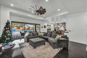 Living room with concrete floors, a tray ceiling, and recessed lighting