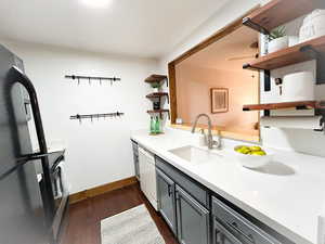 Kitchen featuring open shelves, freestanding refrigerator, gray cabinetry, dishwasher, and dark wood-type flooring