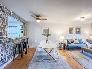 Dining area with wood finished floors, ceiling fan, and wallpapered walls