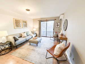 Living room featuring a wall mounted AC and wood finished floors
