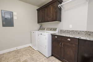 Washroom featuring cabinet space, electric panel, and washing machine and dryer