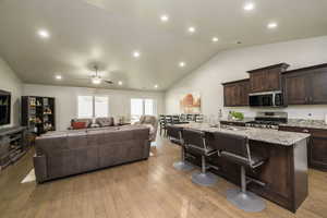Living room with lofted ceiling, light wood-style flooring, a ceiling fan, and recessed lighting