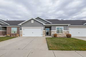 Ranch-style house featuring concrete driveway, stone siding, and stucco siding