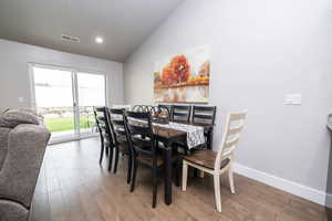 Dining room with vaulted ceiling, wood finished floors, and recessed lighting