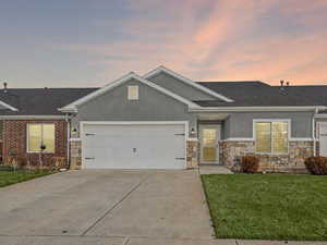 View of front of property featuring stucco siding, driveway, a front yard, and an attached garage