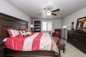 Bedroom with light carpet, a ceiling fan, and a textured ceiling