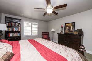 Carpeted bedroom featuring ceiling fan and baseboards
