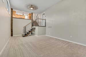 Unfurnished living room with light colored carpet and stairway