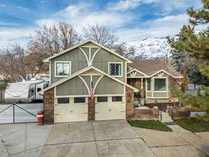 Tri-level home with brick siding, board and batten siding, concrete driveway, a mountain view, and an attached garage
