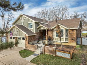 View of front of home featuring board and batten siding, roof with shingles, brick siding, and concrete driveway