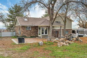 Back of property featuring french doors, brick siding, a patio, and a shingled roof