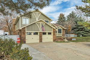 View of front of house with brick siding, concrete driveway, and board and batten siding