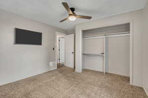 Unfurnished bedroom with light colored carpet, ceiling fan, and a closet