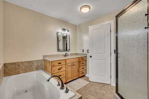 Bathroom with a whirlpool tub, vanity, and a stall shower