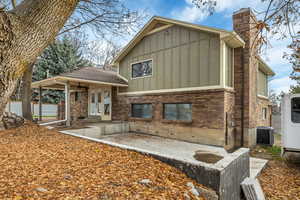 View of side of home featuring board and batten siding, a patio area, brick siding, a chimney, and french doors