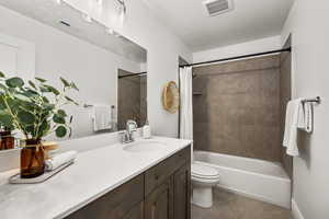 Bathroom featuring vanity, shower / bath combination with curtain, and a textured ceiling