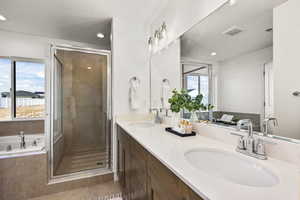 Bathroom with double vanity, a shower stall, a garden tub, and healthy amount of natural light
