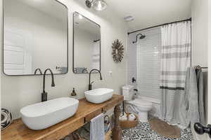 Bathroom with double vanity and shower / tub combo with curtain