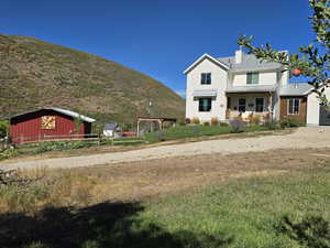 View of front of home with an outbuilding, a chimney, driveway, and a porch