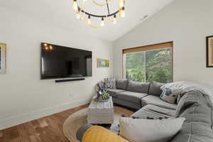 Living area featuring wood finished floors, lofted ceiling, and a chandelier
