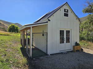 View of side of property featuring board and batten siding, an outbuilding, a mountain view, a metal roof, and a standing seam roof