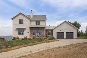 View of front facade with covered porch, driveway, a garage, and a front lawn