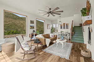 Living room featuring stairs, dark wood-style flooring, and a ceiling fan