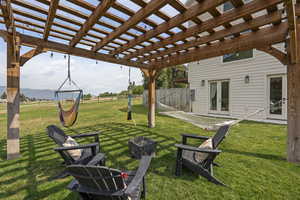View of yard featuring a pergola, a fire pit, a patio area, and french doors