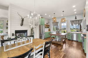 Dining space with a chandelier, dark wood-style floors, recessed lighting, and a multi sided fireplace