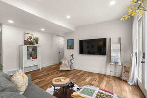 Living area with light wood-style flooring and recessed lighting