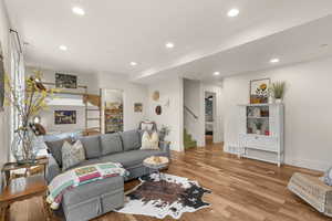 Living room with stairway, light wood finished floors, and recessed lighting