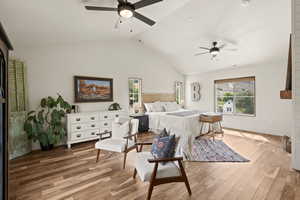 Bedroom with wood finished floors, ceiling fan, and high vaulted ceiling