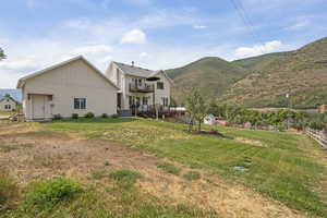 Rear view of property featuring a deck with mountain view, board and batten siding, and a yard