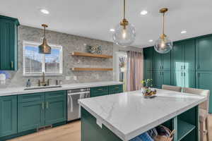 Completely remodeled kitchen with teal cabinets, open shelves, light stone countertops, hanging light fixtures, and recessed lighting