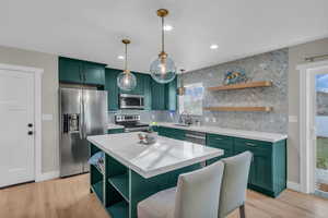 Kitchen featuring open shelves, a kitchen island, green cabinets, and recessed lighting
