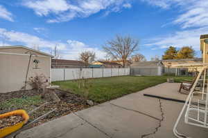 Fenced backyard featuring a storage shed and a patio